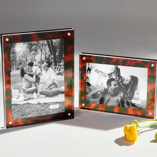 Two photo frames with black and white photos of people, one with a yellow flower on a gray background.