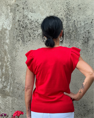 Back view of woman in red sweater facing a wall