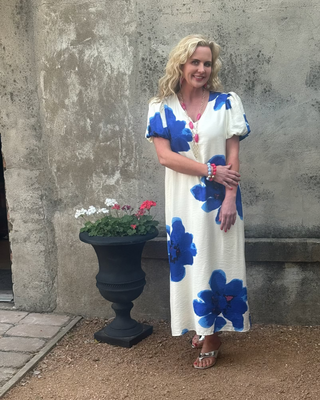 Woman in a maxi dress with stylized cobalt blue flowers on a creme background