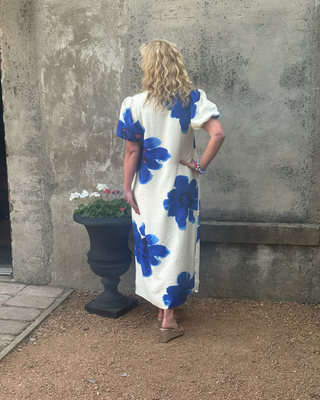 Woman in a maxi dress with stylized cobalt blue flowers on a creme background