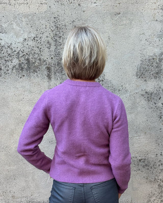 back view of a blonde woman in a purple sweater