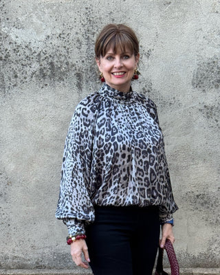 Woman wearing the Entro gray leopard mock neck balloon sleeve blouse with black pants