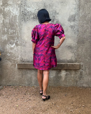 back view ofJodifl magenta brocade shift dress with puff sleeves in a magenta, plum, and red-orange abstract pattern