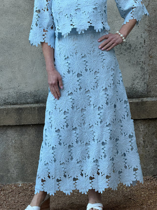 Light blue lace dress worn by a person against a stone wall.