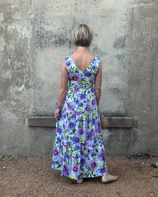 Woman wearing a floral dress standing against a textured wall.