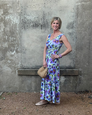 Woman in a floral dress standing against a textured wall.