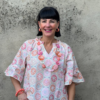 Woman wearing a floral blouse and white pants on a concrete floor