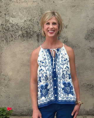 Woman wearing a blue and white patterned top against a textured wall.