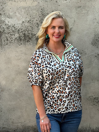 Woman wearing a leopard print blouse with a concrete wall background