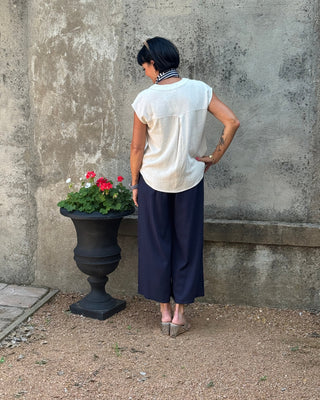 Person standing next to a planter with flowers against a concrete wall.