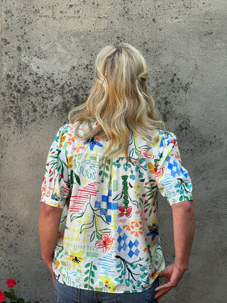 Person wearing a colorful floral blouse on a concrete surface