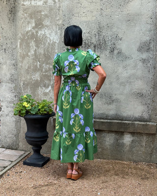 Person wearing a green floral dress standing against a textured wall.