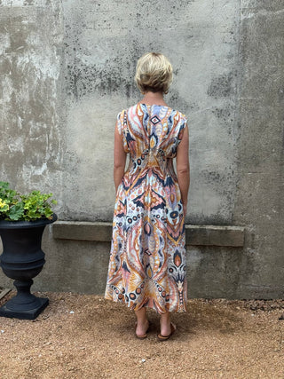 Woman wearing a patterned dress standing against a textured wall.