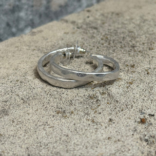 Silver hoop earrings on a textured stone surface