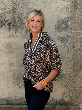 Woman wearing a leopard print top with a gray wall background