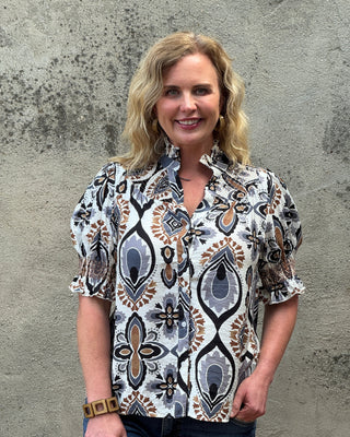 Person wearing a patterned blouse standing on a concrete surface
