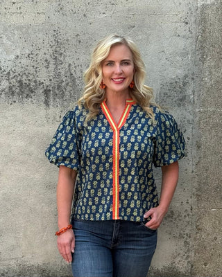 Woman wearing a patterned blouse with a concrete wall background
