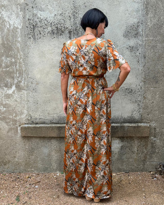 Person wearing a long, patterned dress standing on a concrete floor.