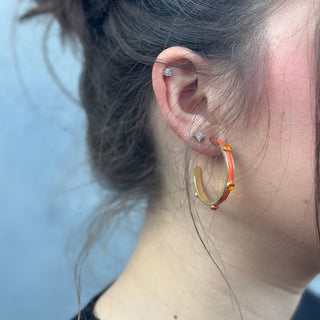 Close-up of an ear wearing gold hoop earrings with a blurred background