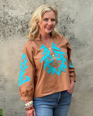woman in a toffe colored top with trquoie applique