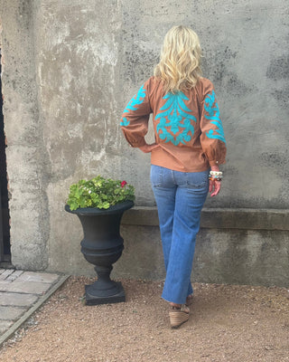 back of woman with jeans and a western top