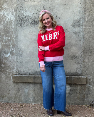 Person wearing a red 'MERRY' sweatshirt standing on a concrete surface.