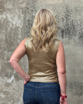 Person wearing a gold top and blue jeans on a concrete floor