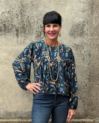 Navy abstract botanical print top by Fun 2 Fun with pintuck pleats, balloon sleeves, and banded hem styled with dark wash jeans and long gold necklace