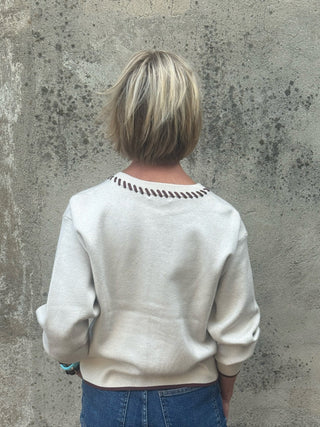 Western inspired cream cardigan with knit horses, horseshoes, zigzag pattern, and brown whipstitch trim on neckline and button placket