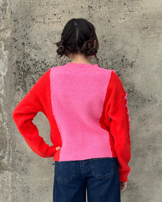 Person wearing a red and pink jacket on a concrete floor