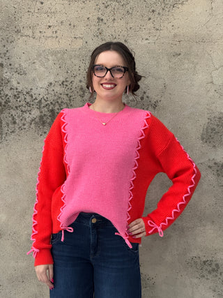 Person wearing a red and pink sweater on a concrete floor
