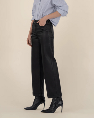 Woman wearing a blue checkered shirt and black pants on a beige background