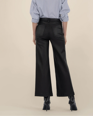 Person wearing a blue striped shirt and black wide-leg pants on a beige background