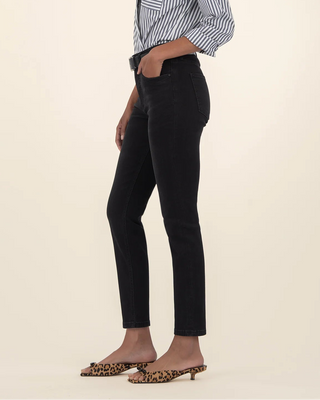 Person wearing a striped shirt and black pants on a beige background