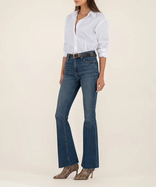 Person wearing a white shirt and blue flared jeans on a beige background