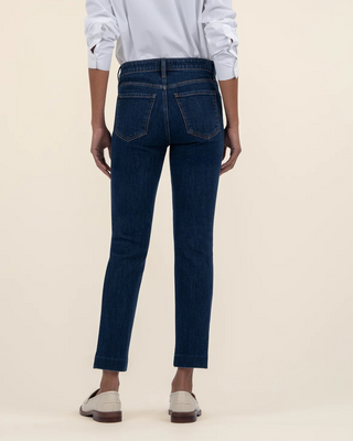 Person wearing a light blue shirt and dark blue jeans on a beige background