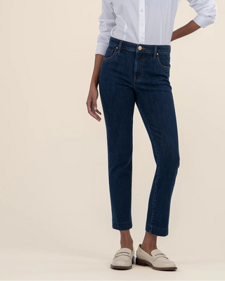 Person wearing a light blue button-up shirt and dark blue jeans on a beige background