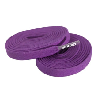 Purple woven elastic shoelaces coiled on a white background, with a silver metal tip showing the brand name BREAD.