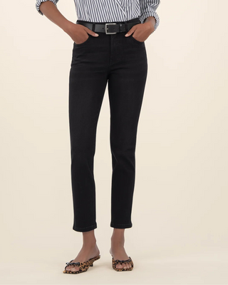 Person wearing a striped shirt and black pants on a beige background