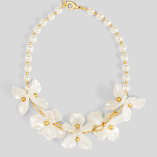 Necklace with white floral pendants and gold accents on a light gray background