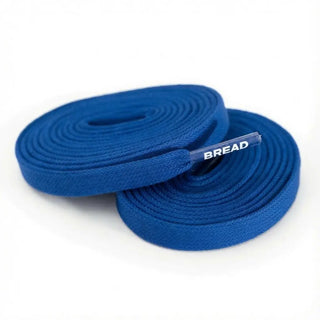 A pair of coiled blue shoelaces with a small white 'BREAD' brand tag, shown on a clean white background.