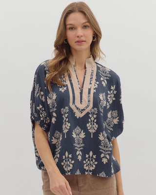 Woman wearing a blue floral blouse with lace details on a white background