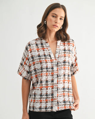 Woman wearing a patterned blouse with short sleeves on a white background
