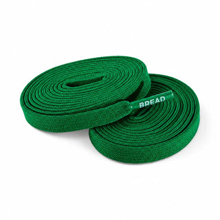 Two coiled green woven shoelaces with a clear plastic tag that reads 'BREAD' in white text, set against a plain white background.